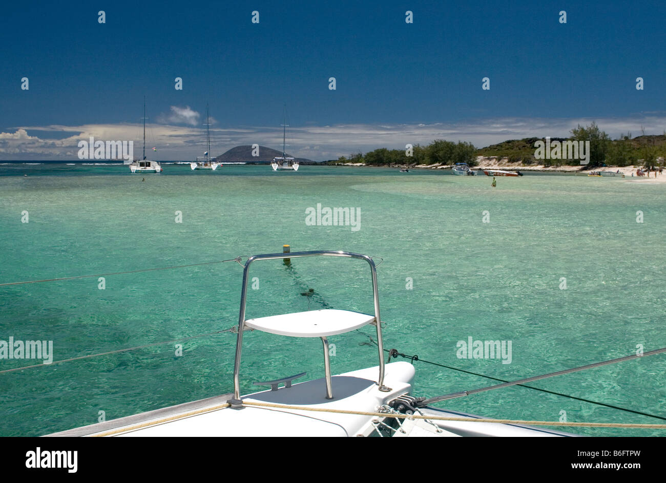 Catamarans moored off coral reef between Ile Plate & Ilot Gabriel with turquoise coral sea, blue sky and Ile Ronde - Mauritius. Stock Photo
