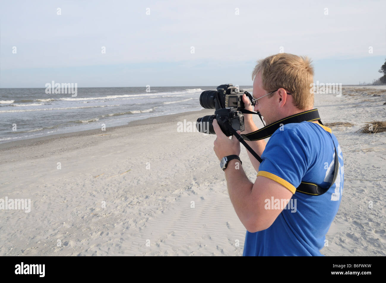An enthusiastic photographer uses two cameras to photograph the Atlantic Ocean at Hunting Island, South Carolina, USA in April. Stock Photo