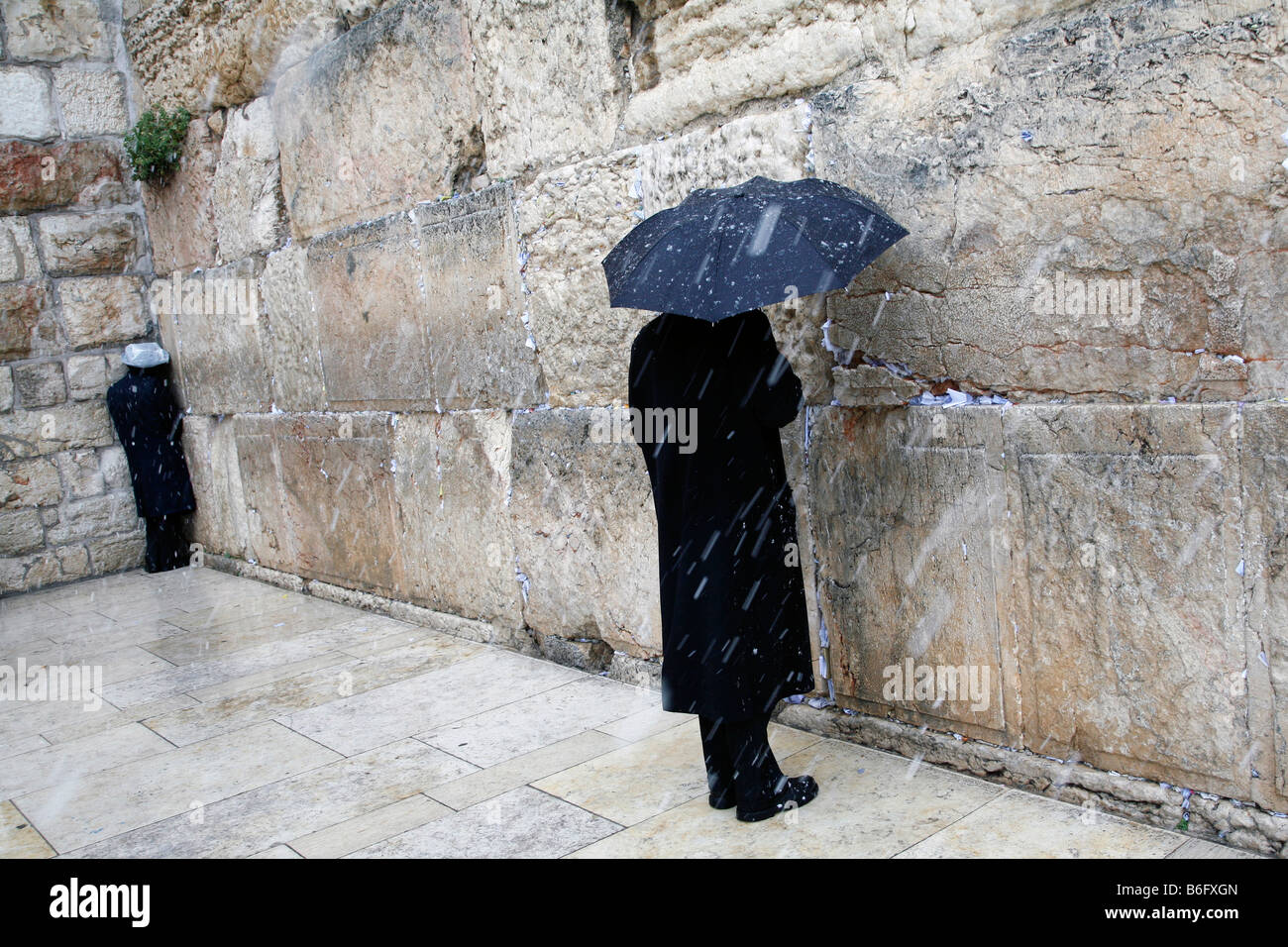 Religious Jews praying at the Western Wall in in the Old City of Jerusalem during a snow storm. Stock Photo