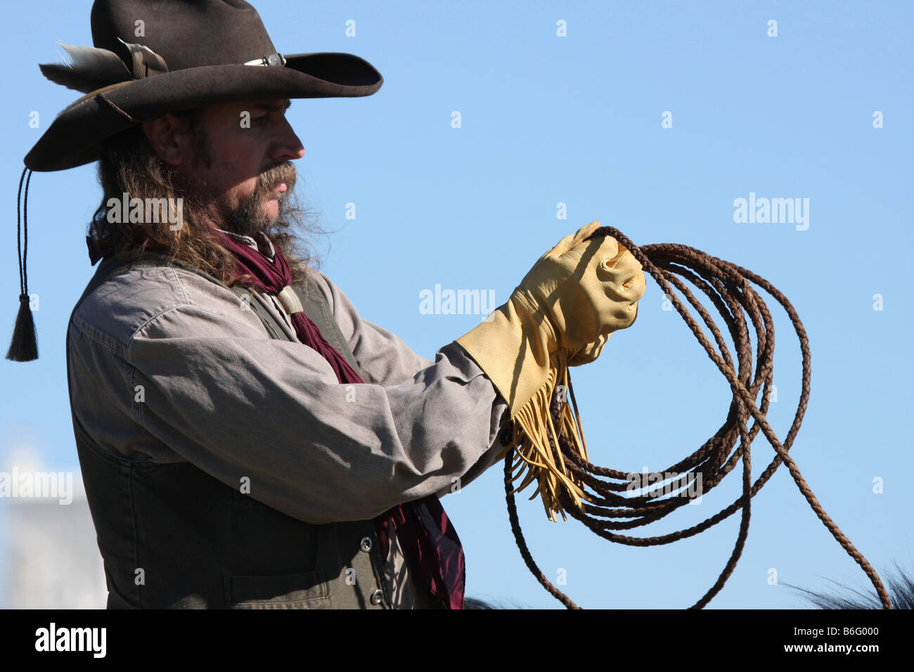 A cowboy on horseback bringing in his rope for catching cattle Stock
