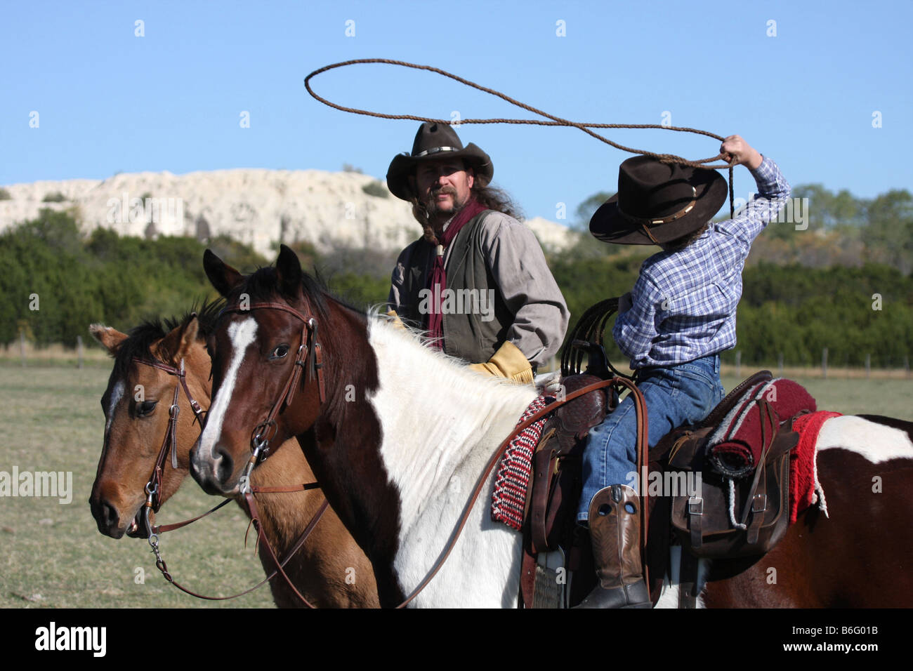 A young cowboy shows his dad how well he his throwing the rope while ...