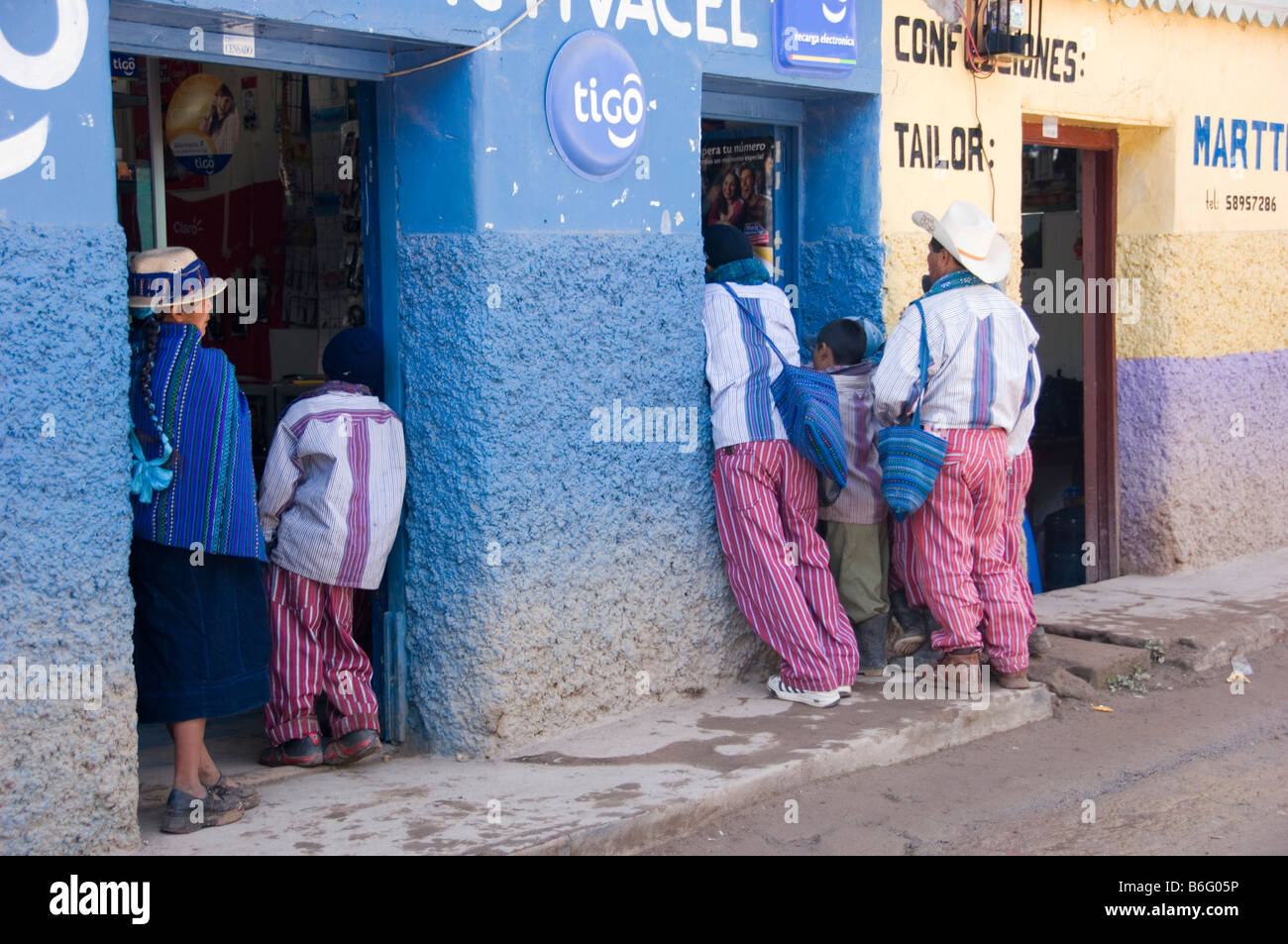 Men and woman in traditional dress in front of a shop in Todos Santos Cuchumatan. Western Guatemala. Stock Photo