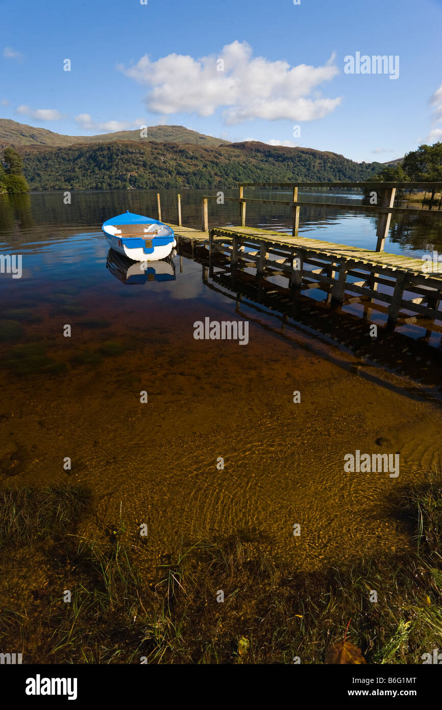 Rowing boat tied to wooden walkway on Loch Lomond, with Ben Lomond in