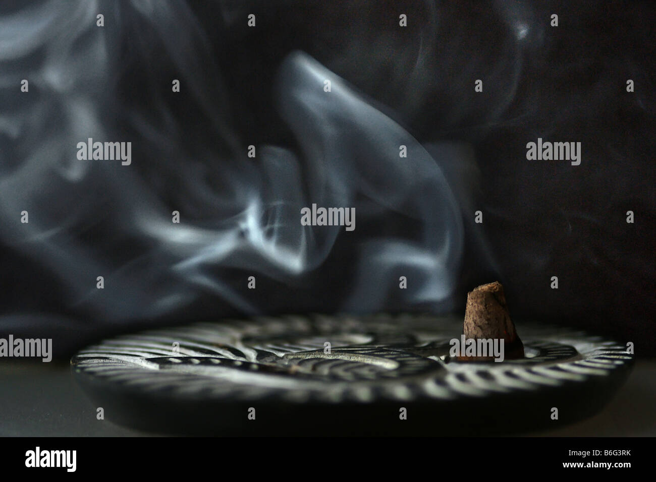 Tranquil incense smoke plume salvia divinorum smudge abstraction burning on small plate on black background Stock Photo