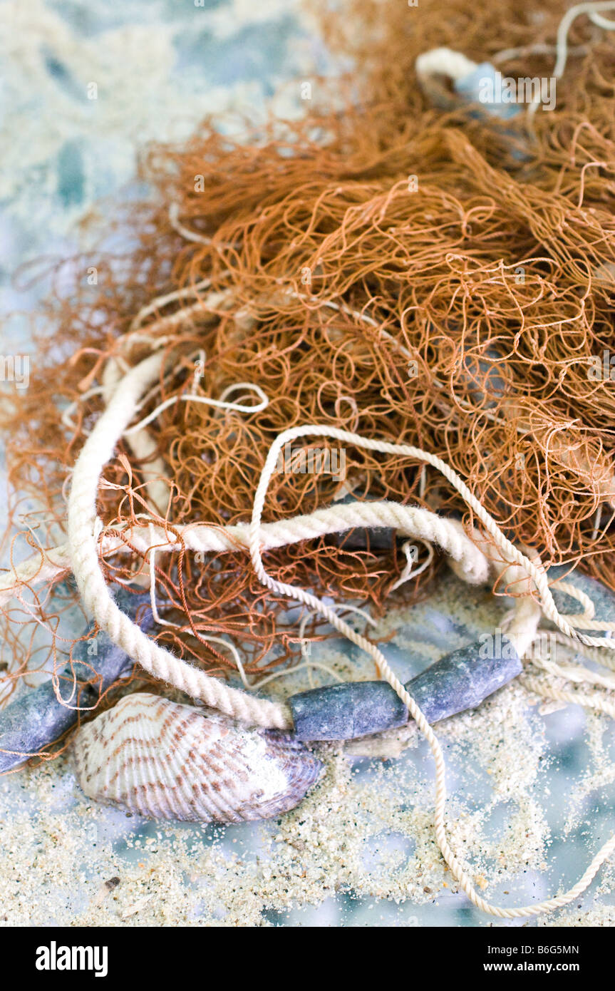 Close-up of fishnet, rope, seashell, and sand. Stock Photo