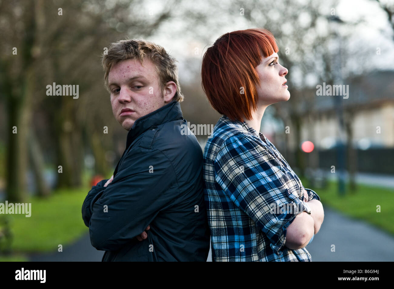 A young couple man and woman having an argument standing back to back not speaking to each other; sulking, not talking Stock Photo