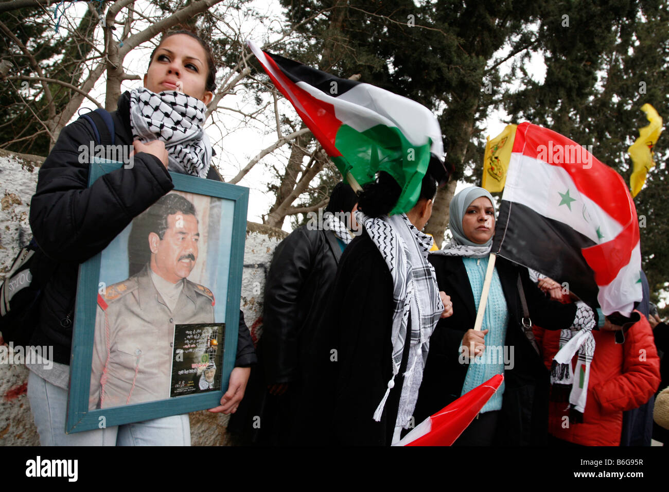 Palestinian women posing with Palestinian and Iraqi flags and a portrait of Saddam Hussein in the West Bank. Stock Photo