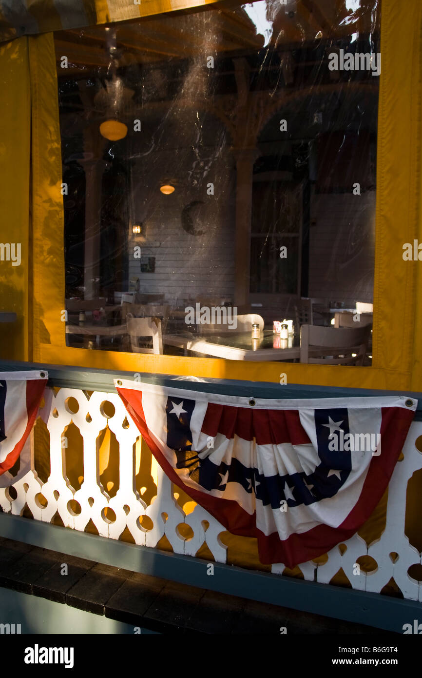A covered cafe porch with Victorian railing hung with stars and stripes buntings. Stock Photo