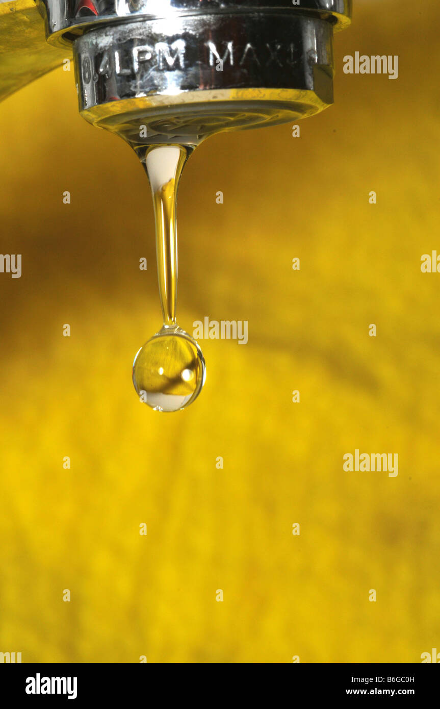 Water dripping from a tap on yellow background Stock Photo