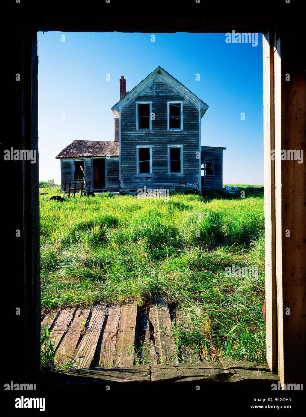 Abandoned farmhouse through barn door Stock Photo