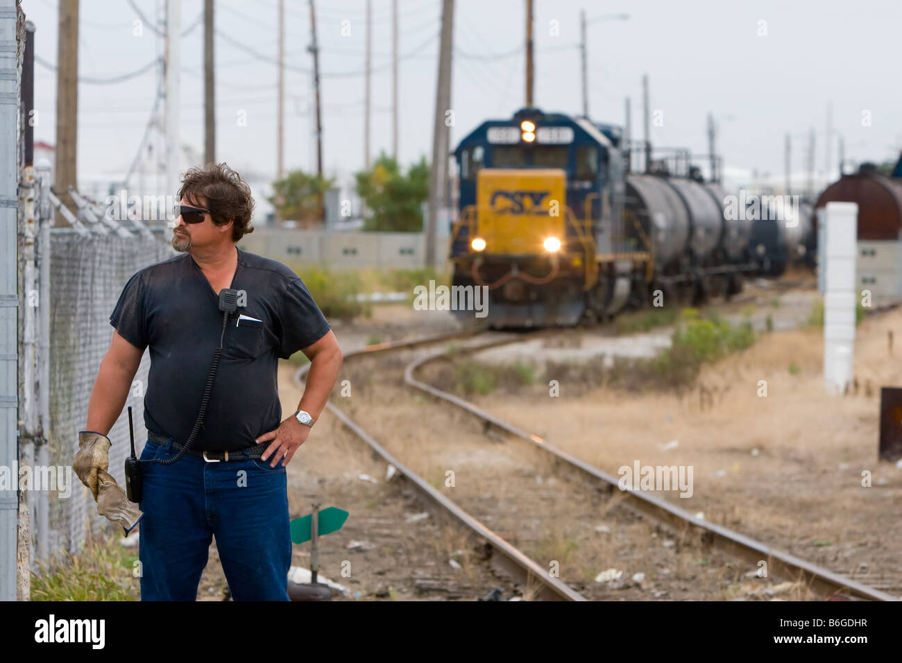 a conductor on a csx freight train stands at a road crossing while freight train conductor