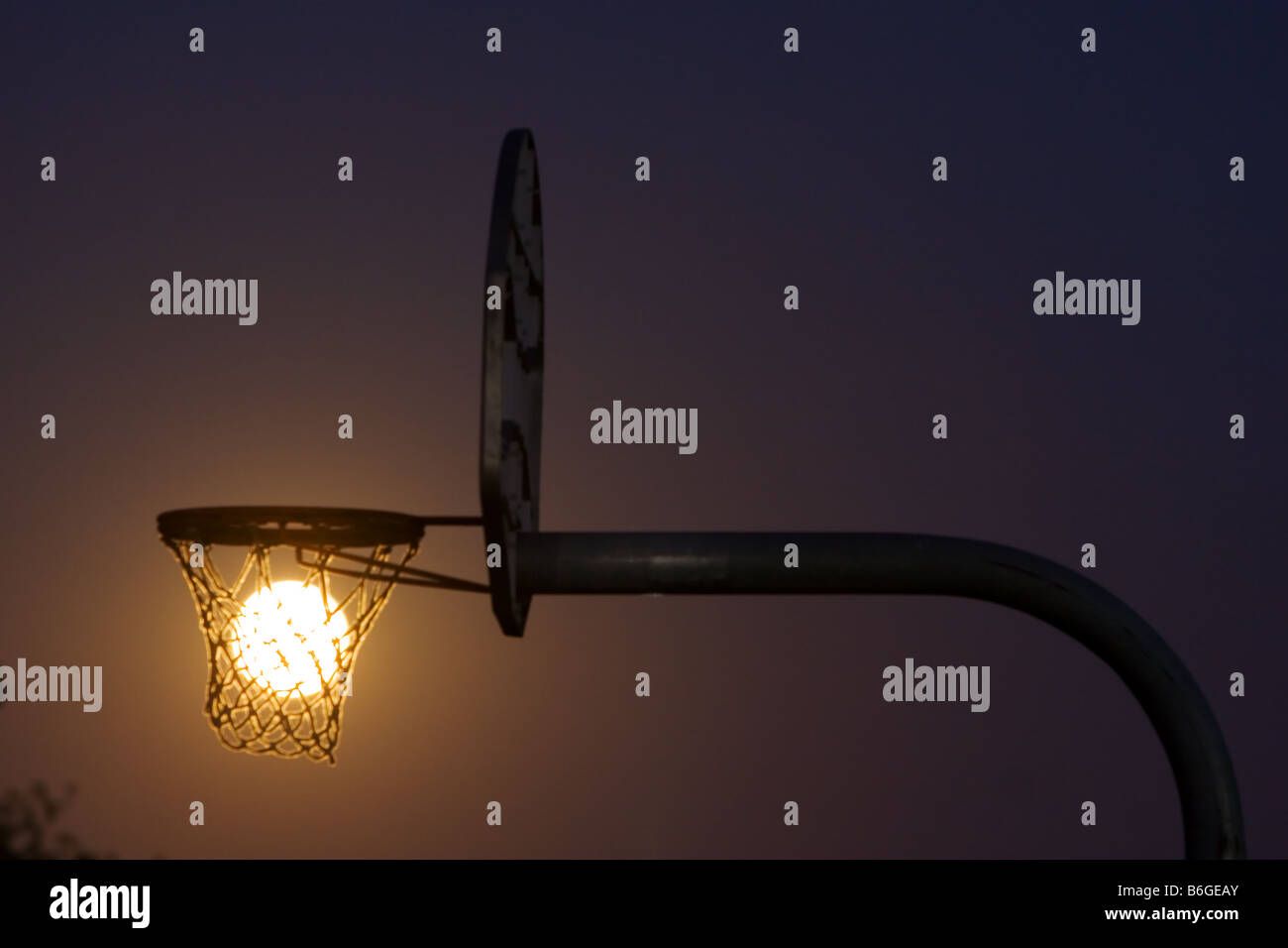 Download A full moon rises through a basketball hoop in a small ...