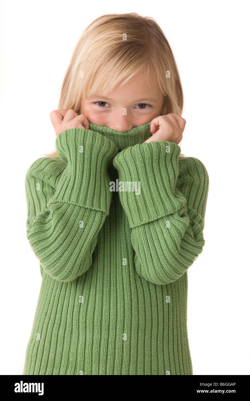Portrait of a seven year old girl holding her turttle neck sweater up over her mouth Stock Photo