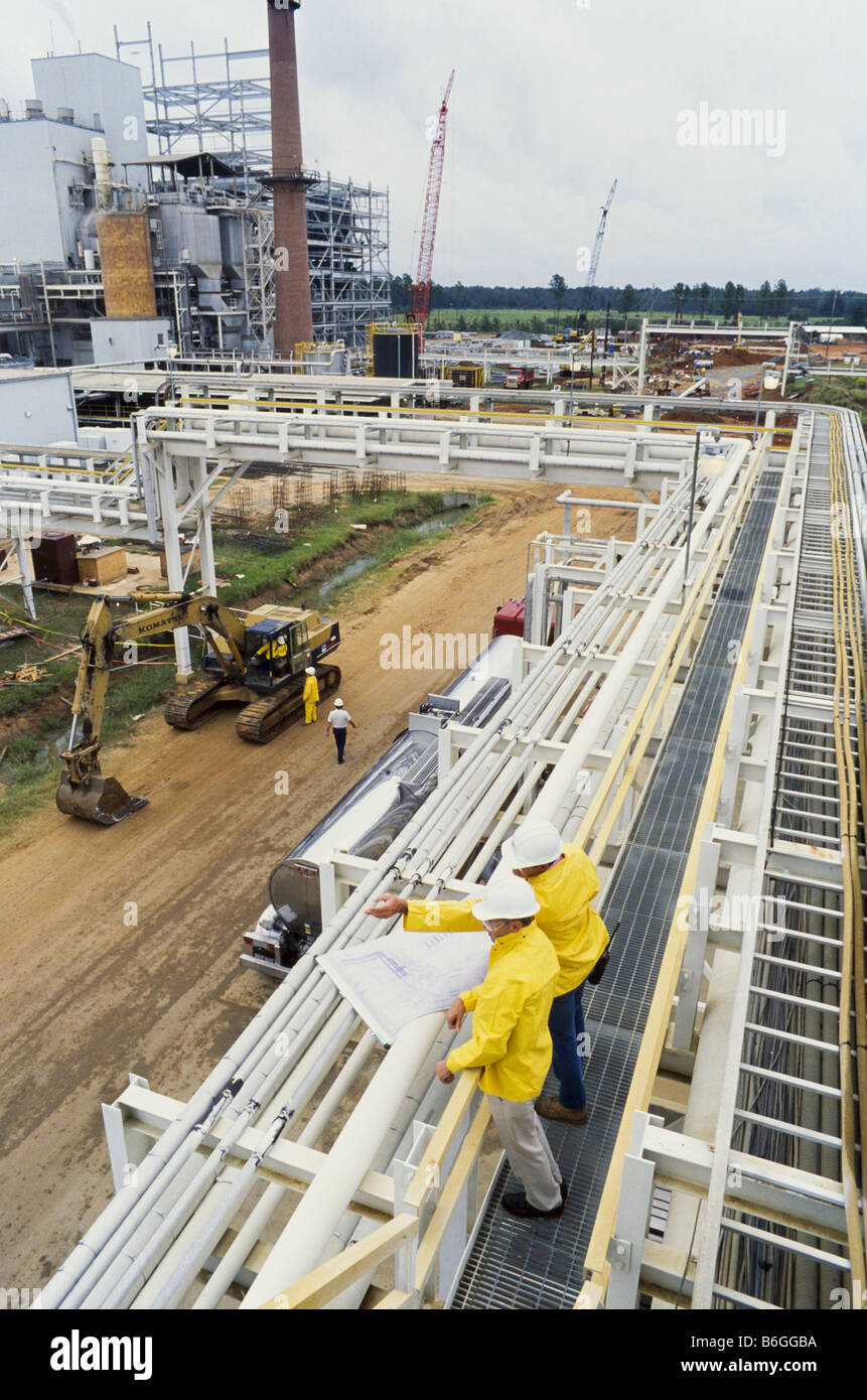 Construction engineers at recycling facility, pipeline leading into factory, Stock Photo