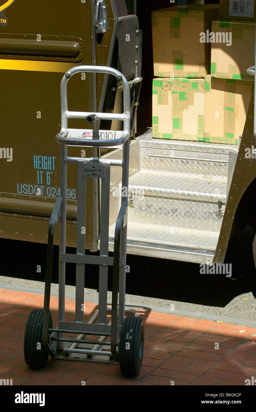 A handtruck waits to be filled with packages from a delivery truck Stock Photo