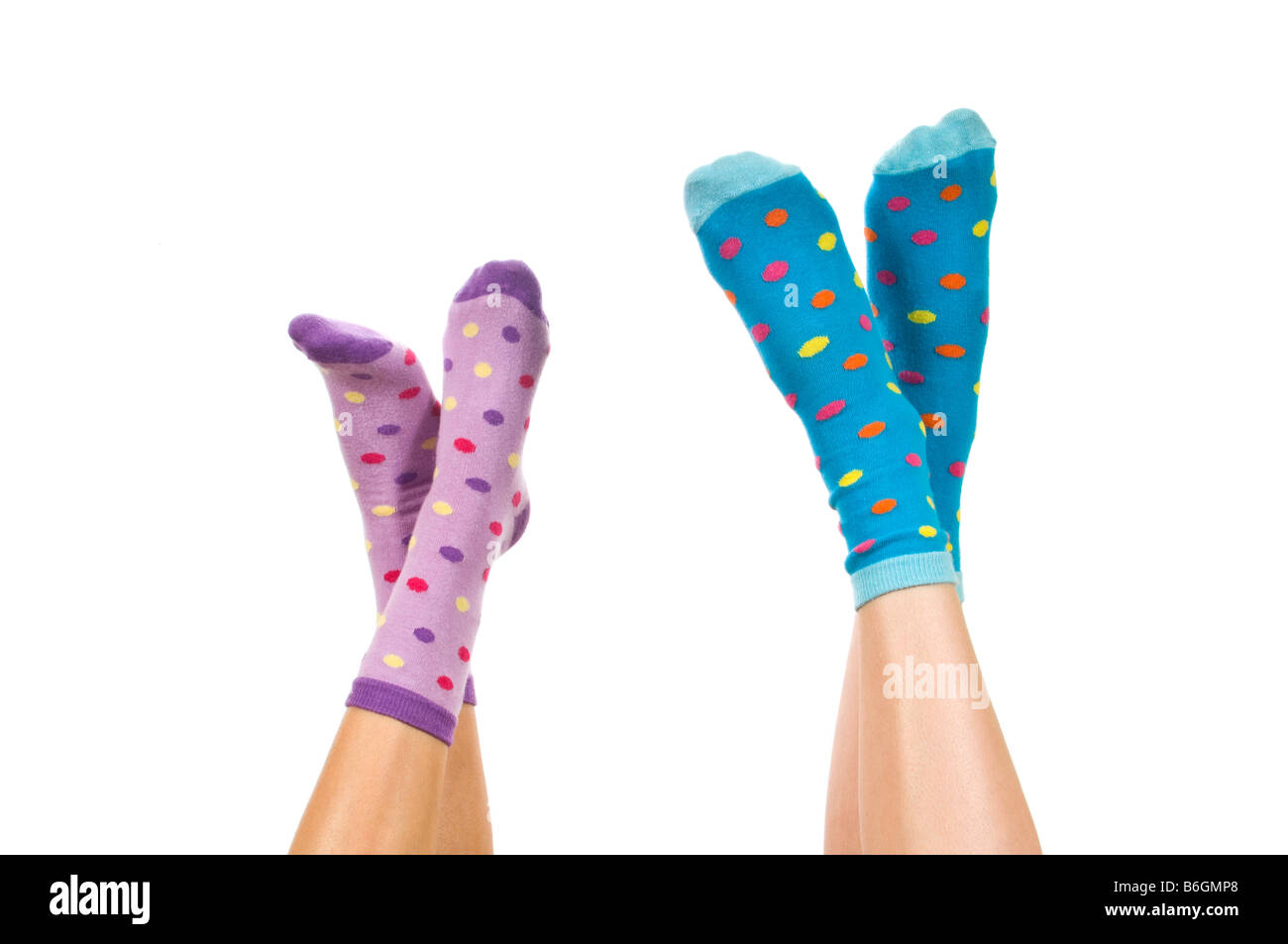 Horizontal close up portrait of two pairs of crossed feet wearing spotty socks in the air against a white background Stock Photo