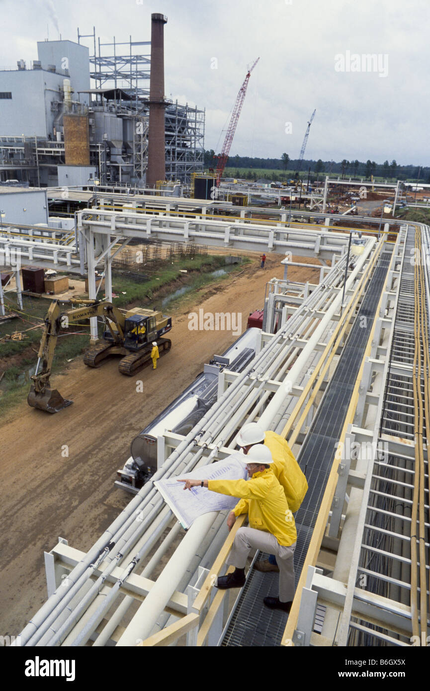 Construction engineers at recycling facility, pipeline leading into factory, Stock Photo