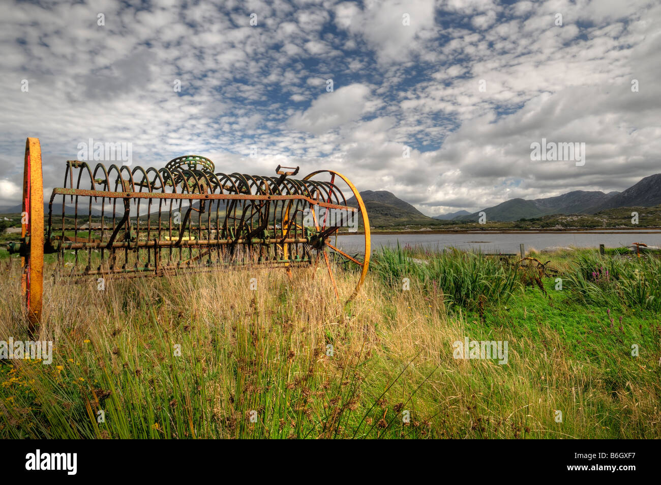Connemara old abandoned farm machinery rural reflection small white clouds reflect clear water twelve bens pins Stock Photo