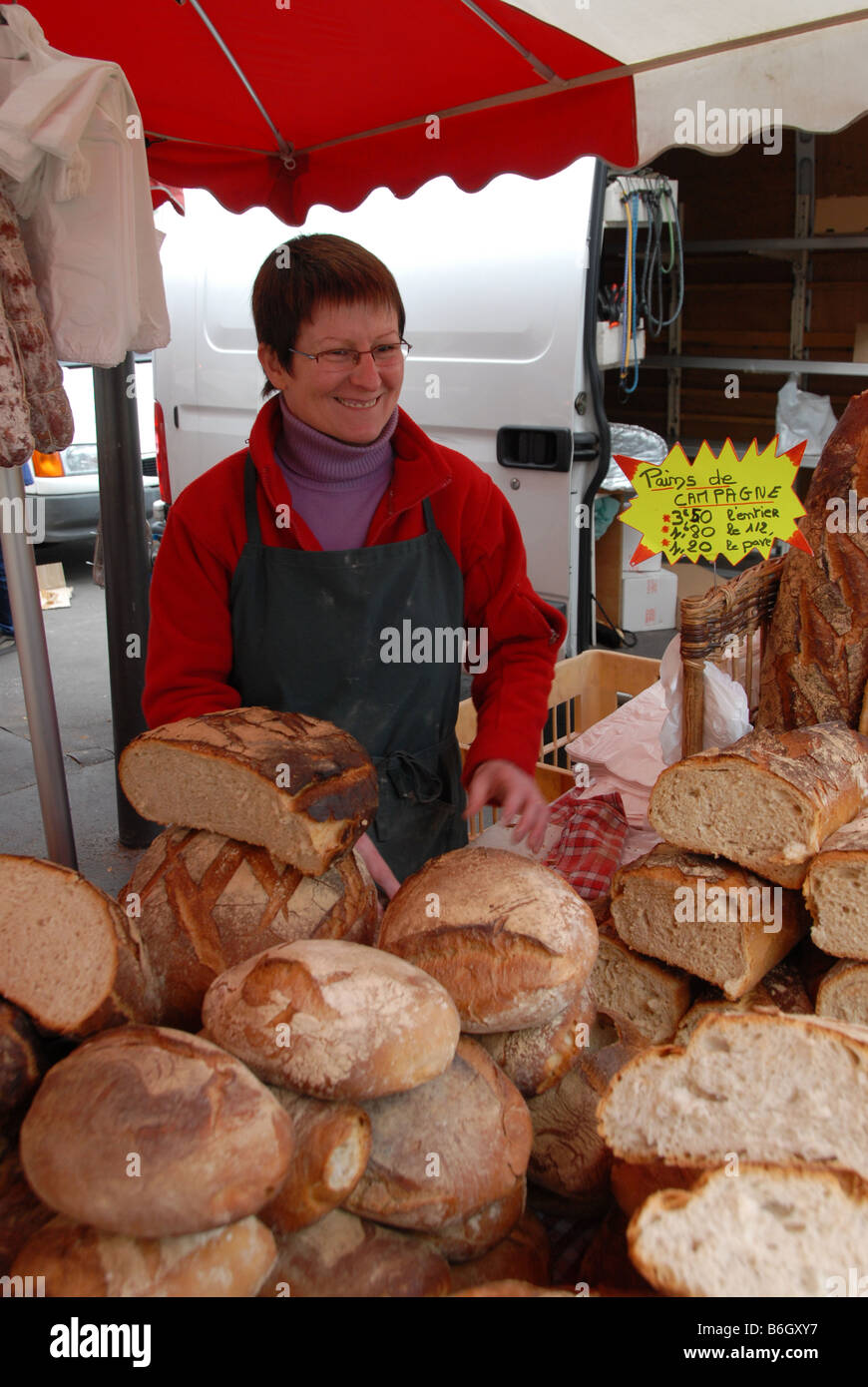 A baker selling freshly baked bread on a market stall at a Sunday