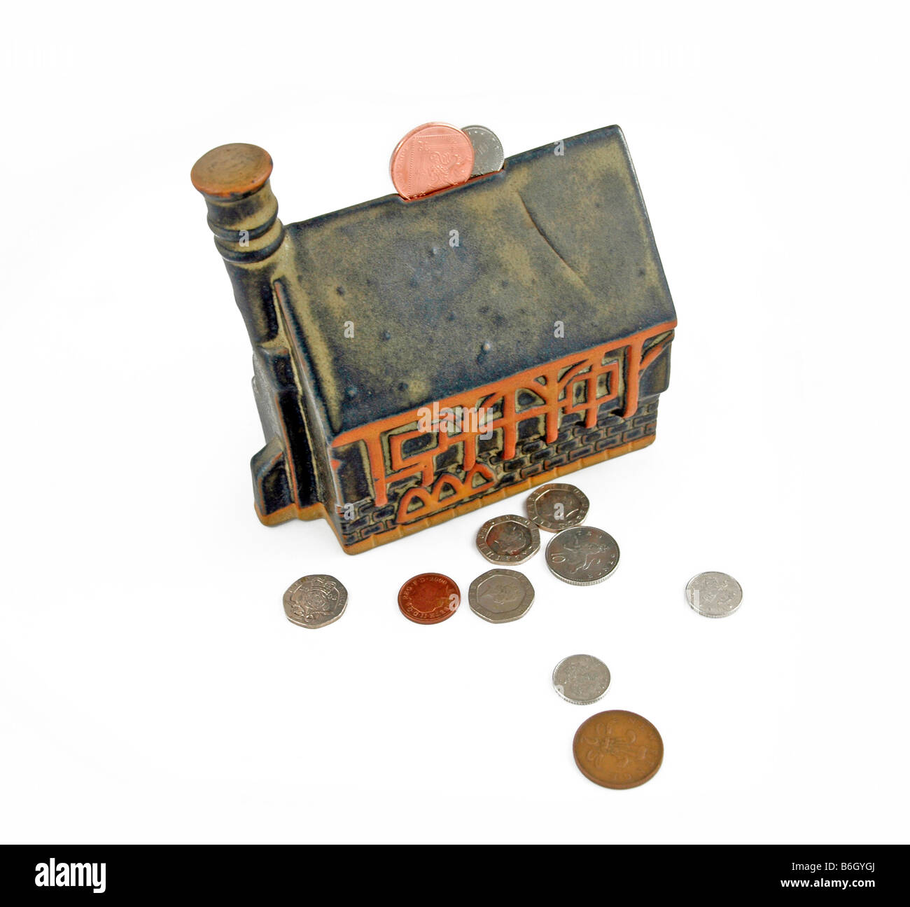 Ceramic church - piggy bank style, with coins around it and with some in the slot. Stock Photo