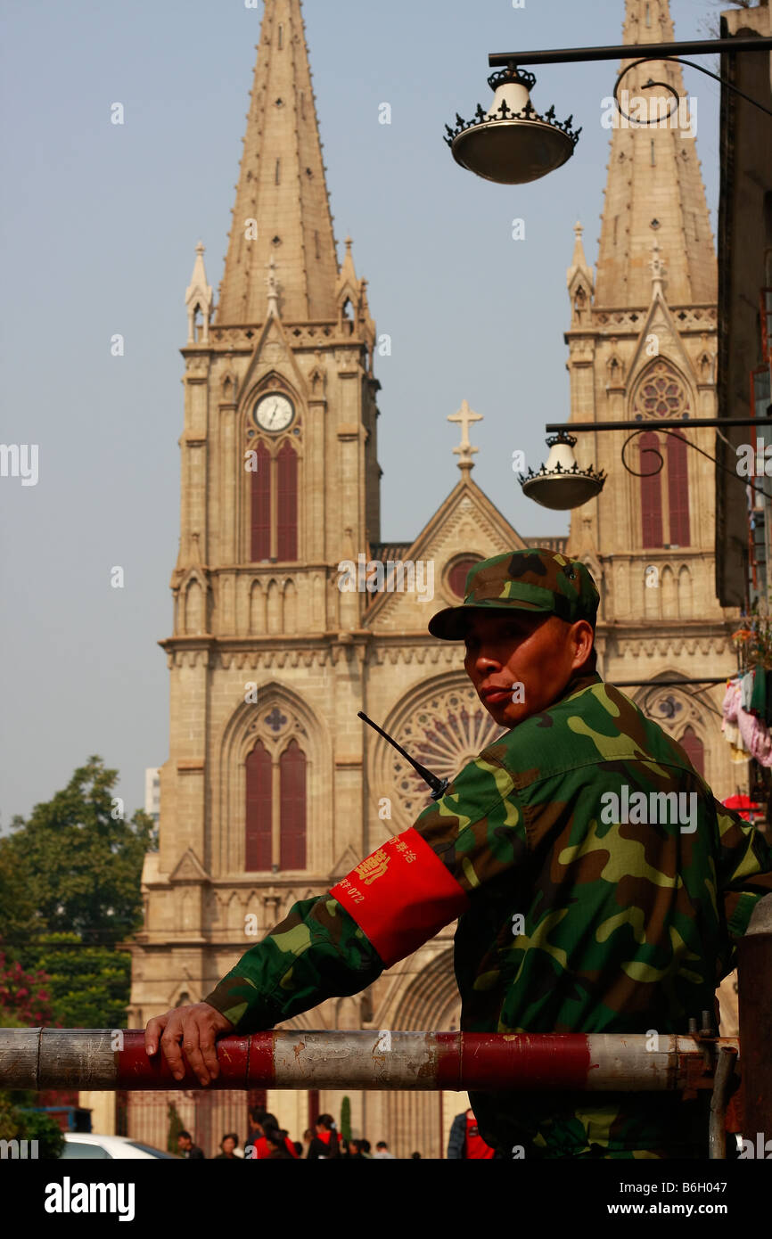 Chinese Uniformed officcer or soldier outside local Church standing guard oustide larges catholic church in Southeast Asia. Stock Photo