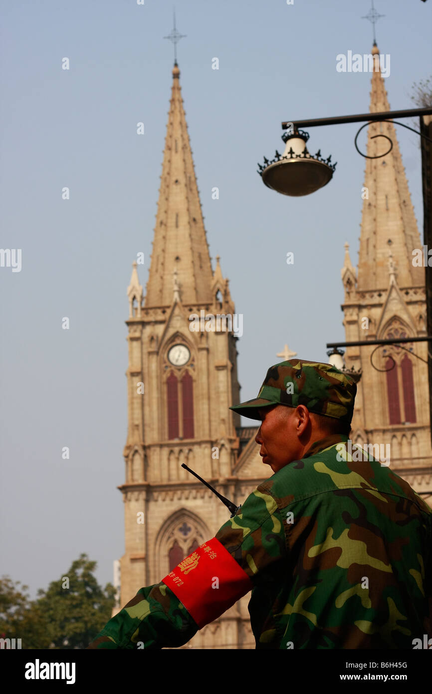 Chinese Uniformed officcer or soldier outside local Church standing guard oustide larges catholic church in Southeast Asia. Stock Photo