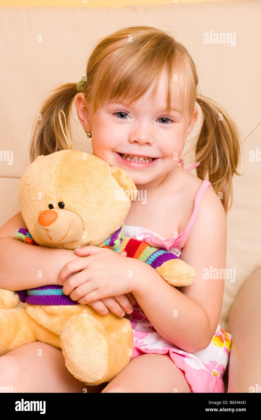 Smiling blond little girl 4 years with plushy bear Stock Photo