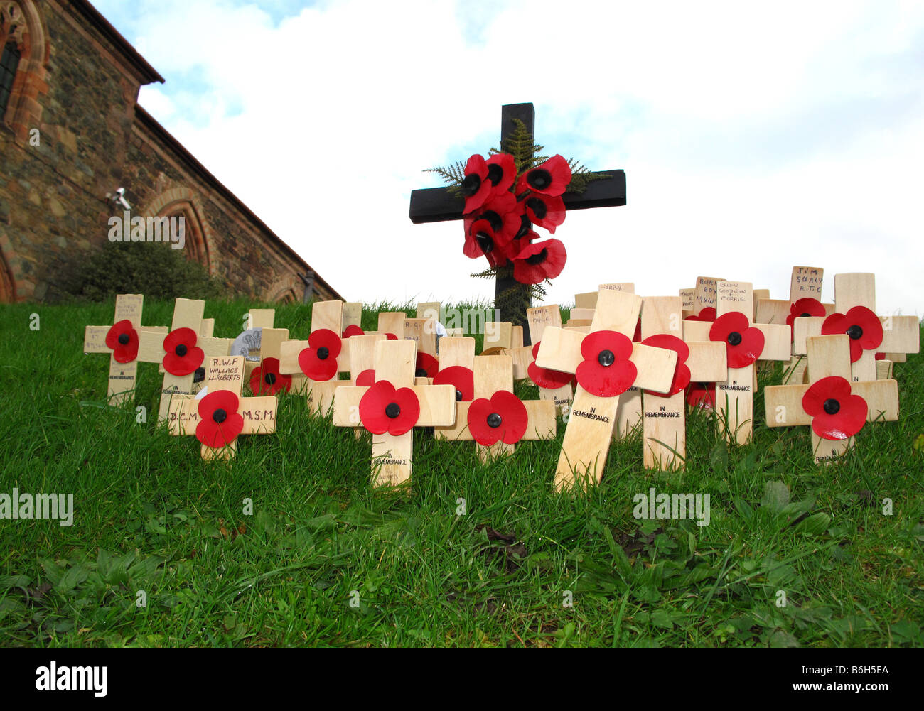 Personal symbolic poppy rememberance crucifixes in churchyard on Remembrance Sunday Stock Photo