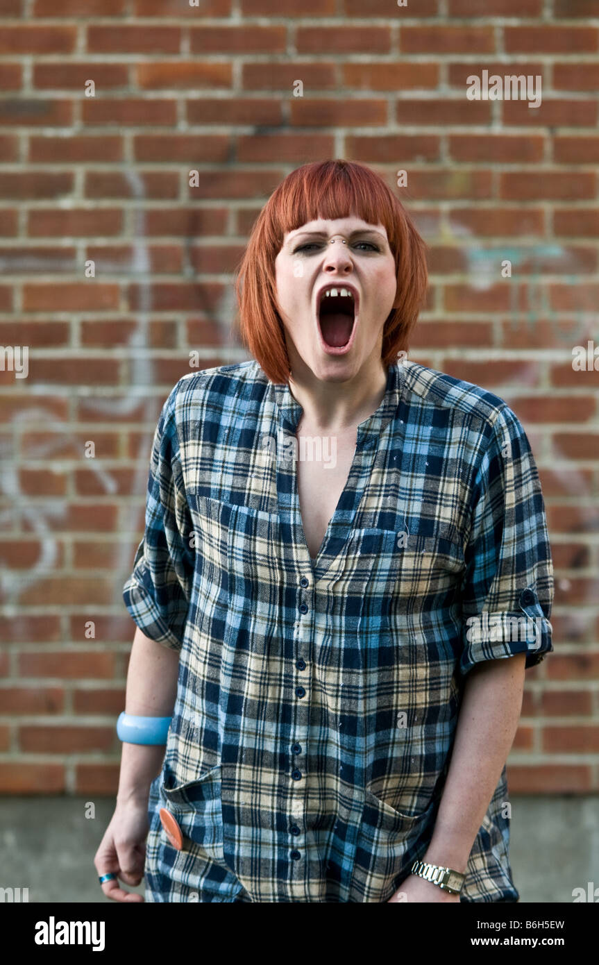 A red haired enraged angry young red haired girl shouting and screaming yelling furiously at the camera Stock Photo