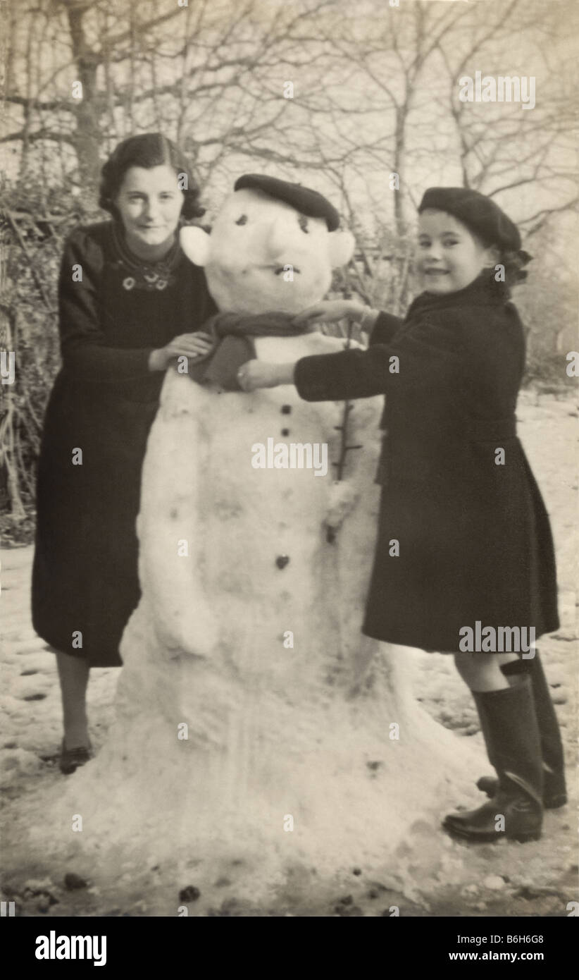 Mother and child building a snowman together in the 1930's or 1940's, pastimes, U.K. Stock Photo