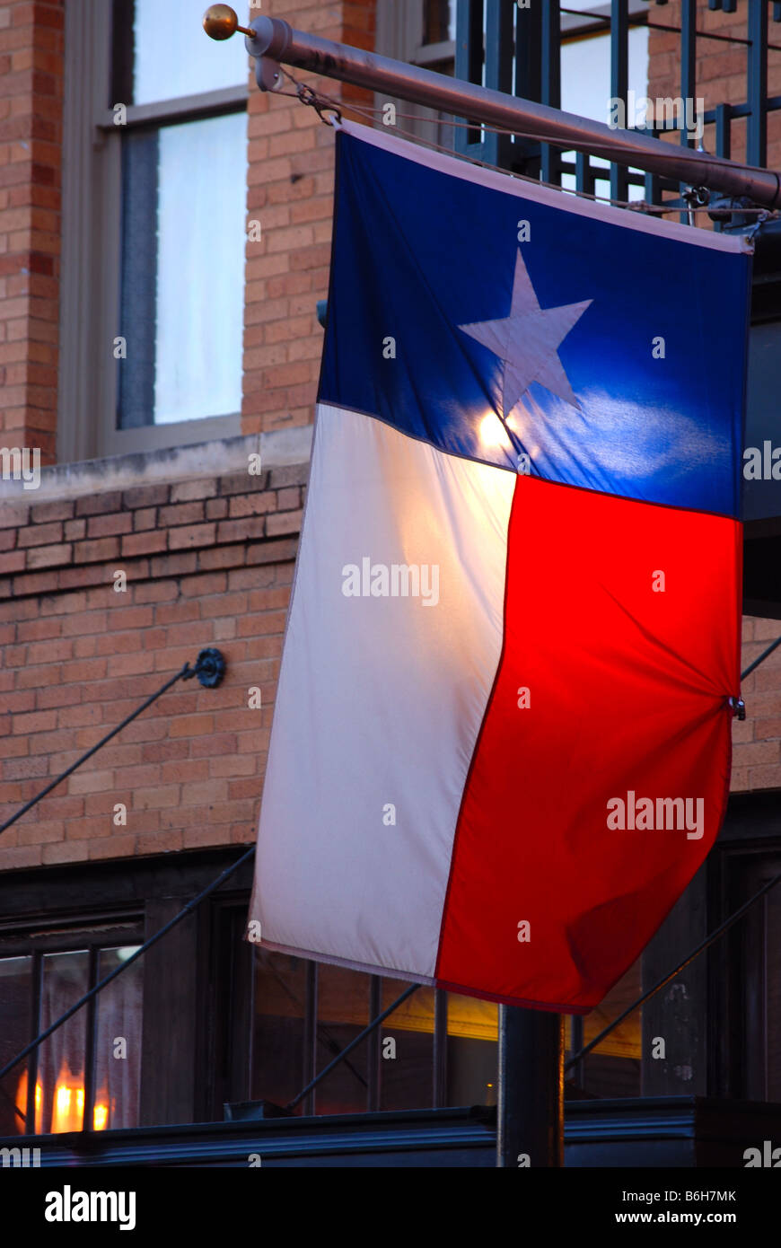 Texas Flag handing outside a buidling with a light shining behind it Stock Photo