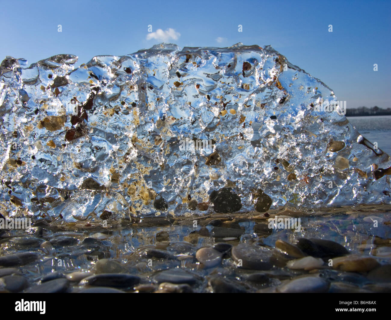 ice plate frozen pond water lake stones blue sky cold freeze surface water winter wintertime landscape involvement inclusion emb Stock Photo