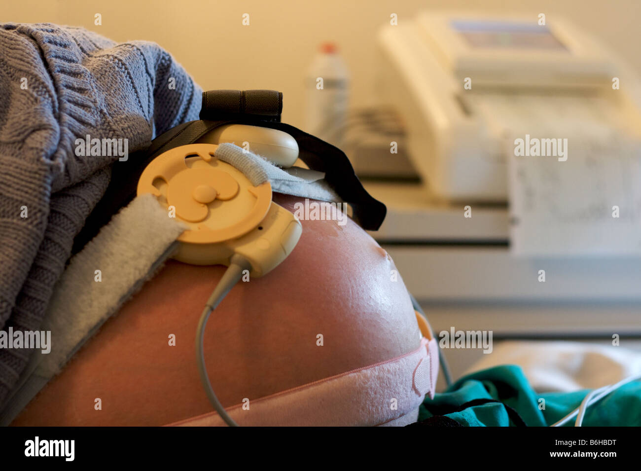 A close-up of a pregnant belly with a fetal monitor attached. Stock Photo