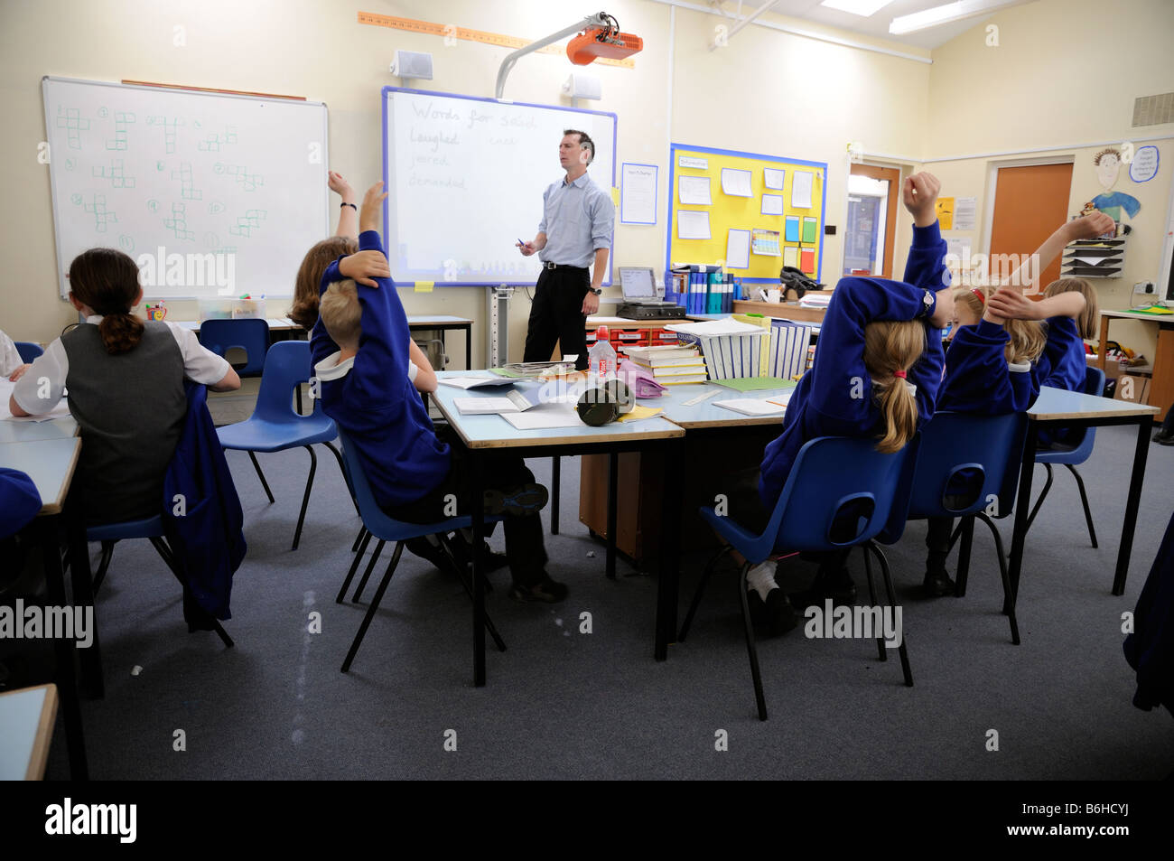 Primary school pupils working in classroom with male teacher Stock Photo