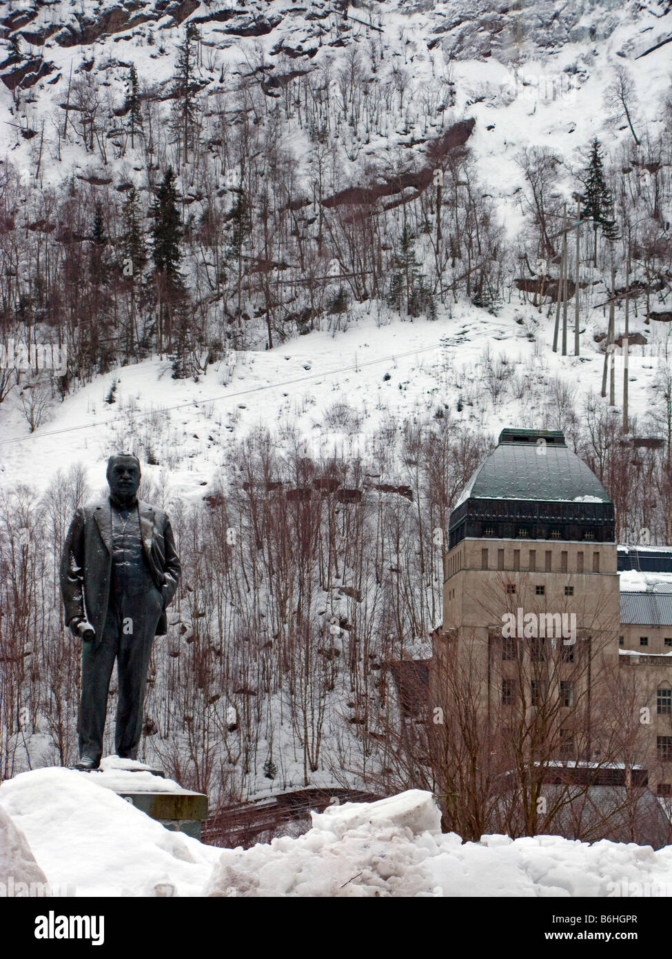 A statue of Sam Eyde, the founder of early hydro electric industry in Rjukan town centre, Såheimhallen power station behind Stock Photo