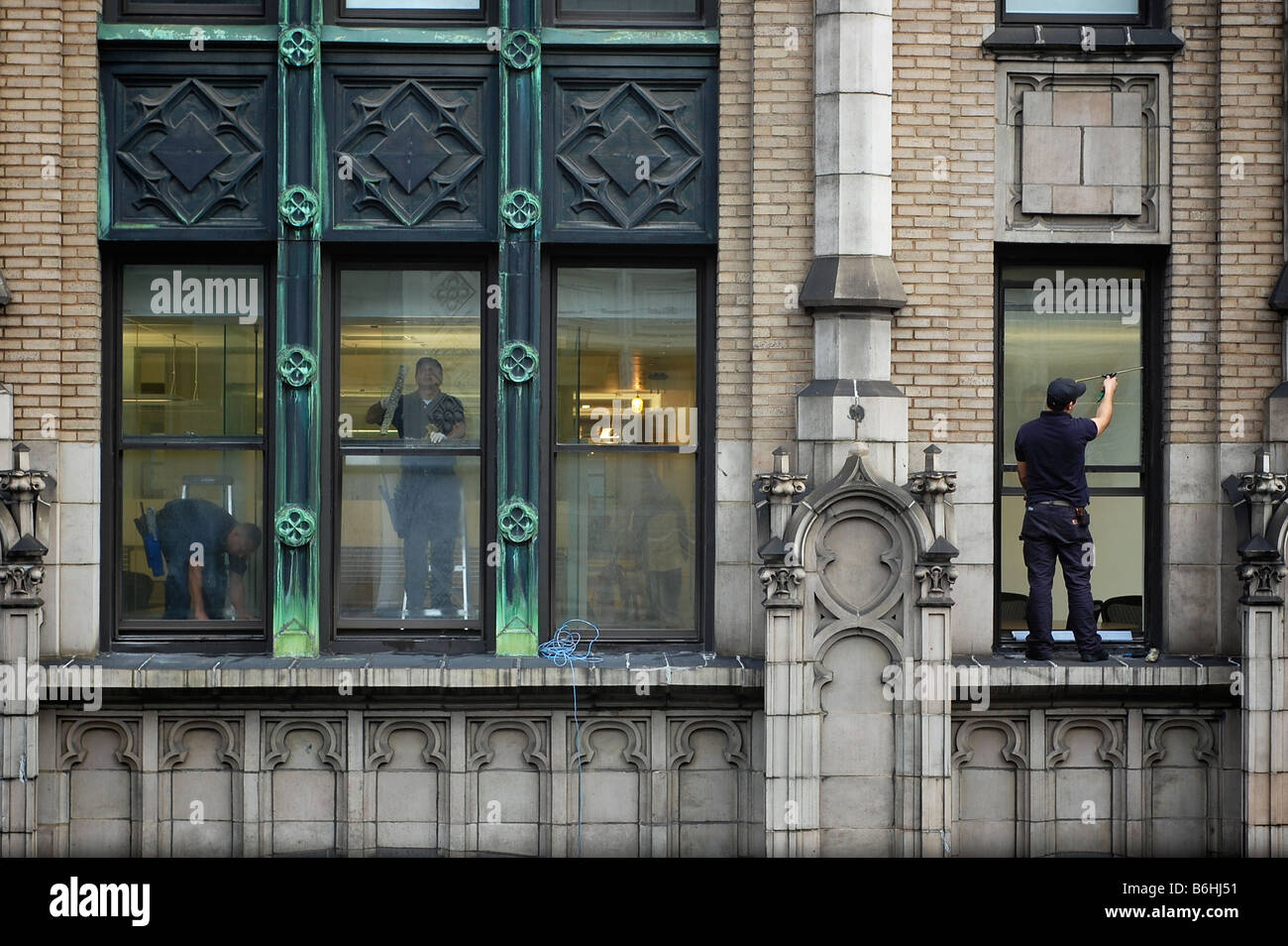 Window Washer Stands on Window Ledge in New York City Skyscraper (For