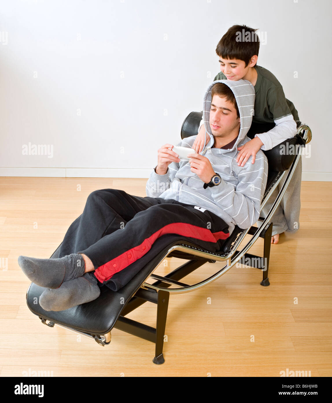 teenager using his iphone with his little brother Stock Photo - Alamy