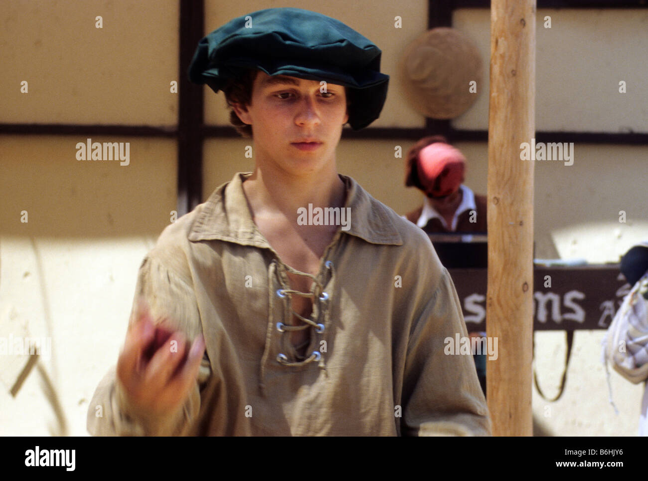 Teen boy in renaissance costume juggles balls at festival in California Stock Photo
