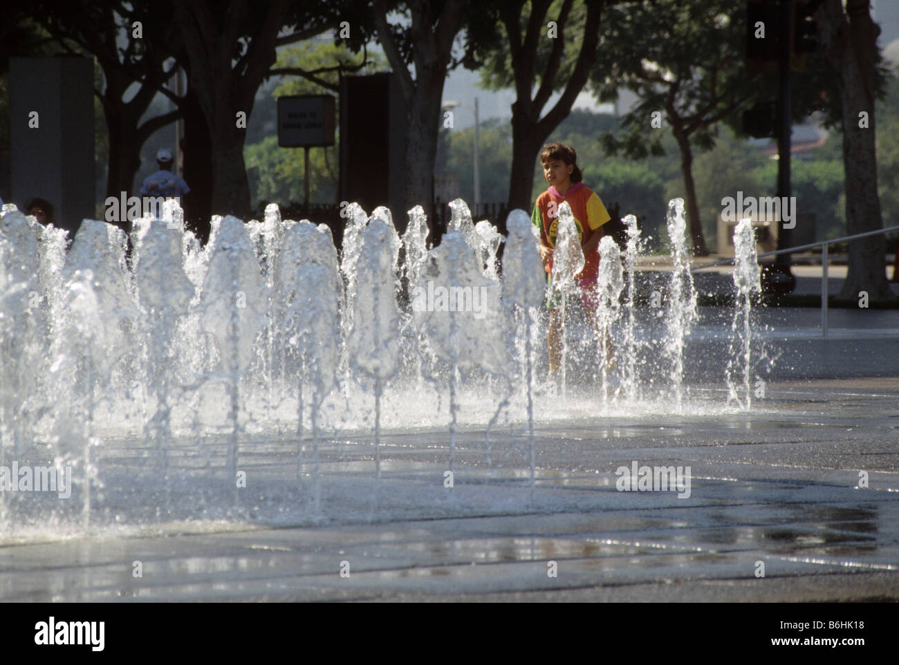 Child plays in fountains that squirt out of the concrete at the Los Angeles County Music Center, California, USA Stock Photo