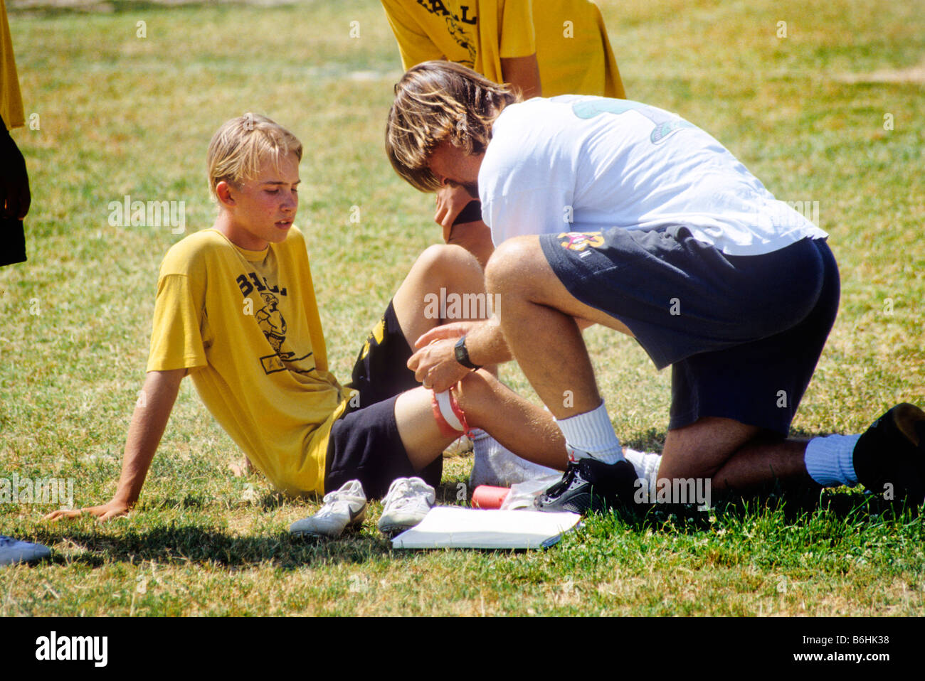 Coach attends injured player in Junior High School football game. Stock Photo