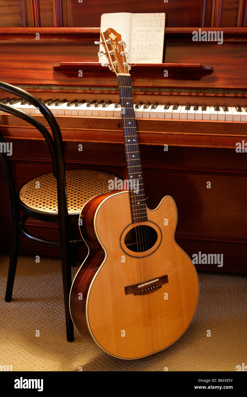 Individually designed  flat top acoustic guitar with  oval sound hole and hand written guitar chord sequences open on piano. Stock Photo