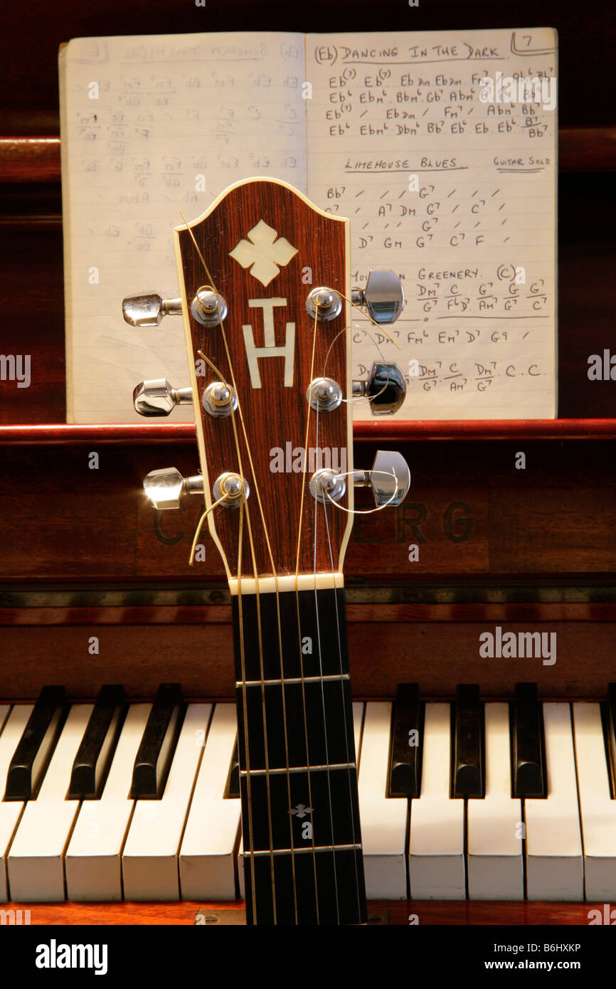 Individually designed acoustic guitar machine head with owners monogram against piano keyboard with guitar chord sequences. Stock Photo