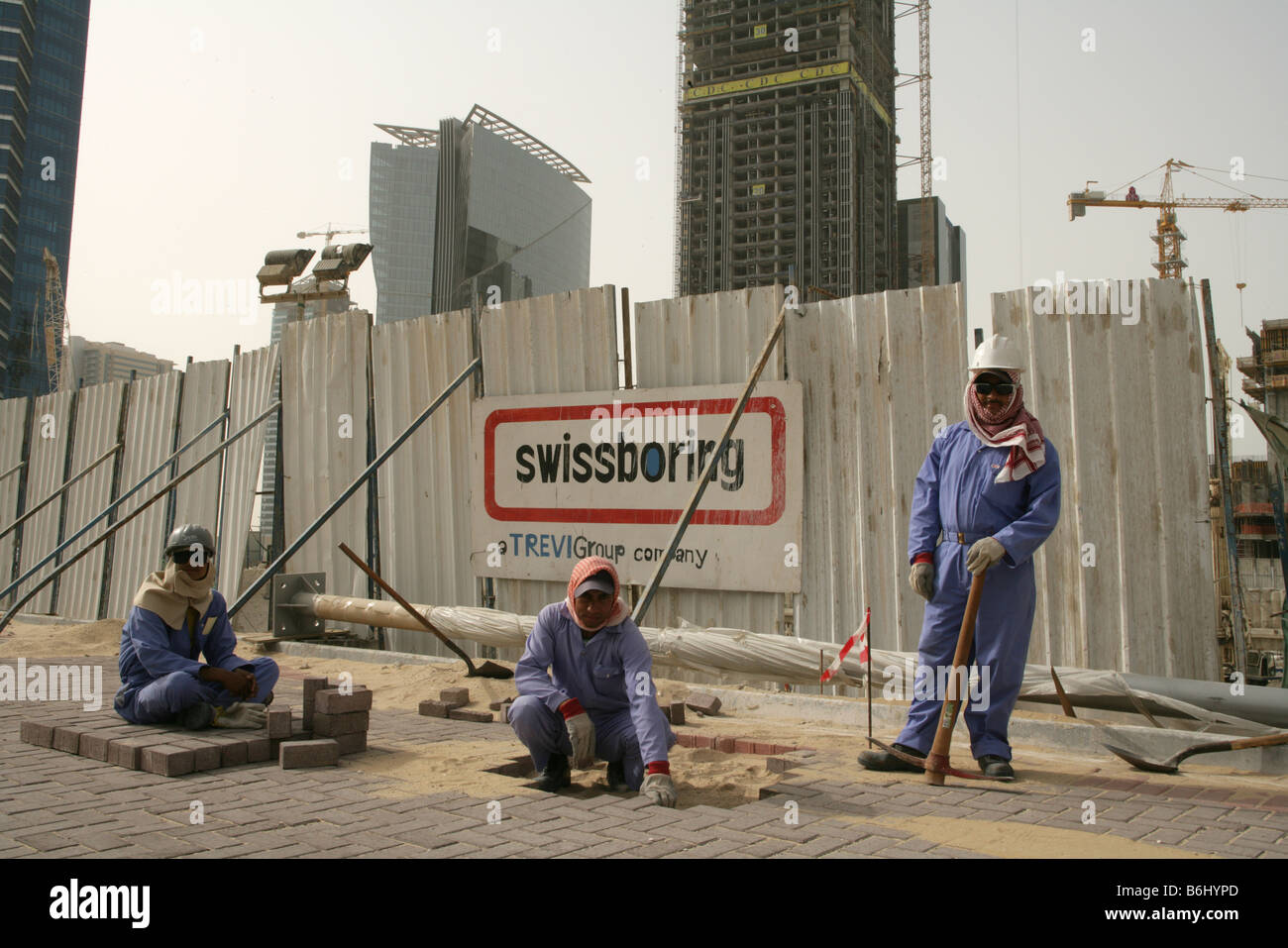 Migrant workers laying bricks for pavement in Doha, Qatar. Stock Photo