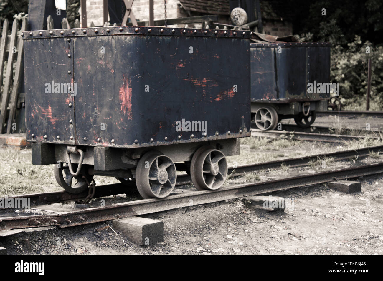 A cart carrying coal on a rail track beside the entrance of a coal mine Stock Photo