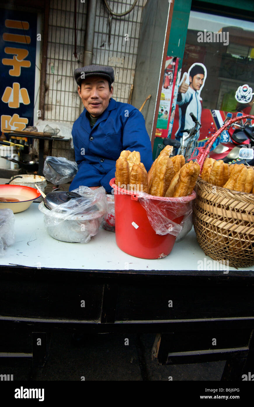 Happy vendor selling deep fried Chinese bread stick breafast and other foods at his street food stall Stock Photo