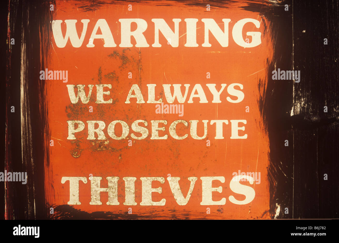 Official red and white weathered sign which has been poorly painted around stating Warning We always prosecute Thieves Stock Photo