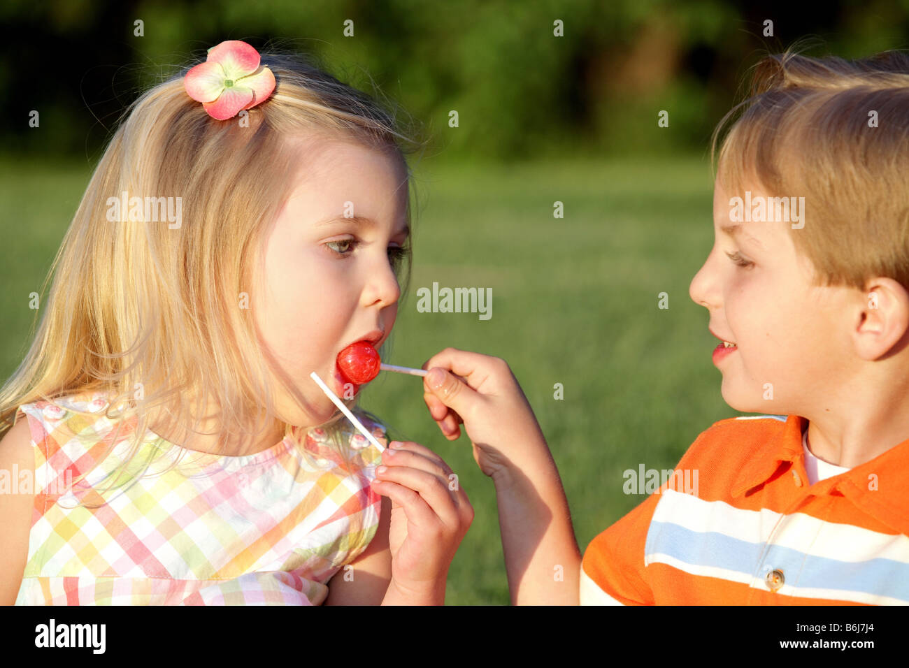 little boy and girl sharing a candy lollipop Stock Photo