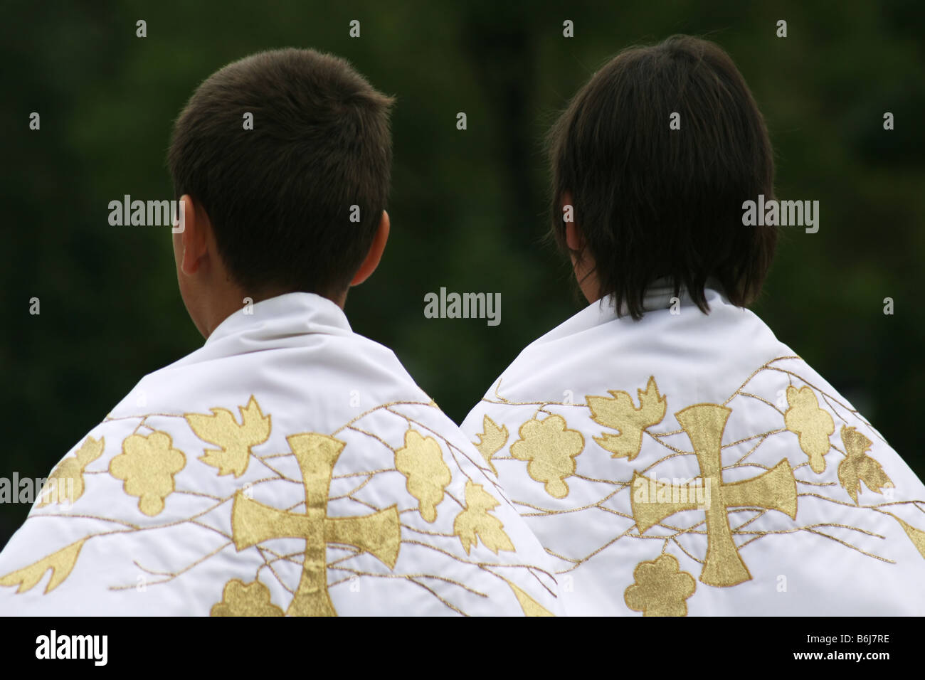 Two Roman Catholic altar servers dressed in church attire. View from the back. Stock Photo