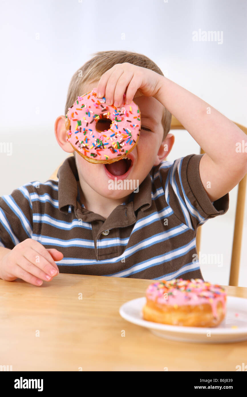 Young boy holding a donut over his eye Stock Photo