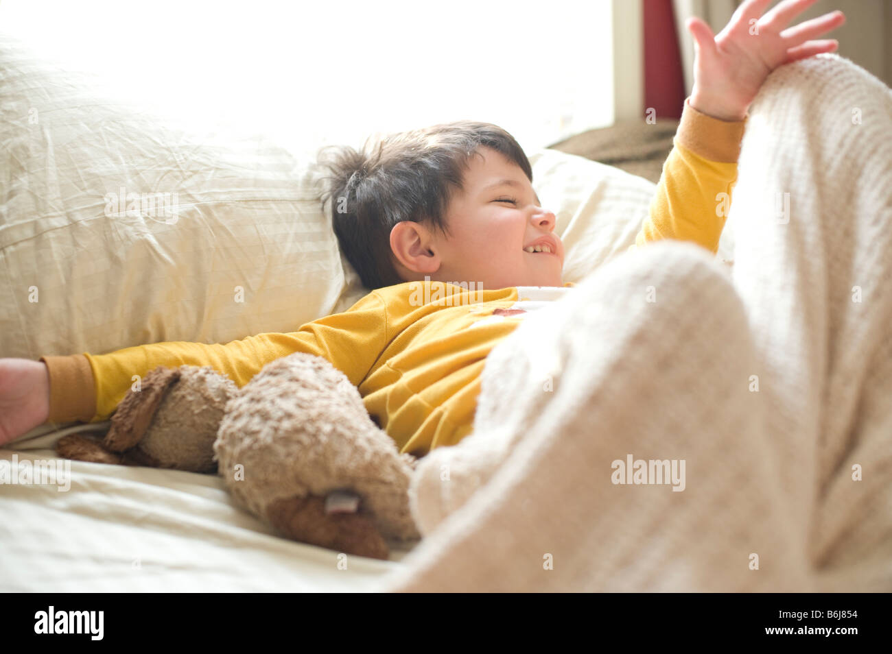 Three year old boy lounges and plays on his parent's bed Stock Photo